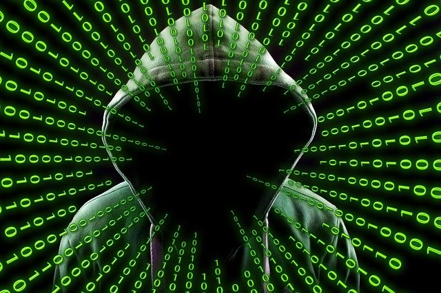 In grünlichem Ton gehaltenes Bild eines mit Kaputze anonymisierten Hackers